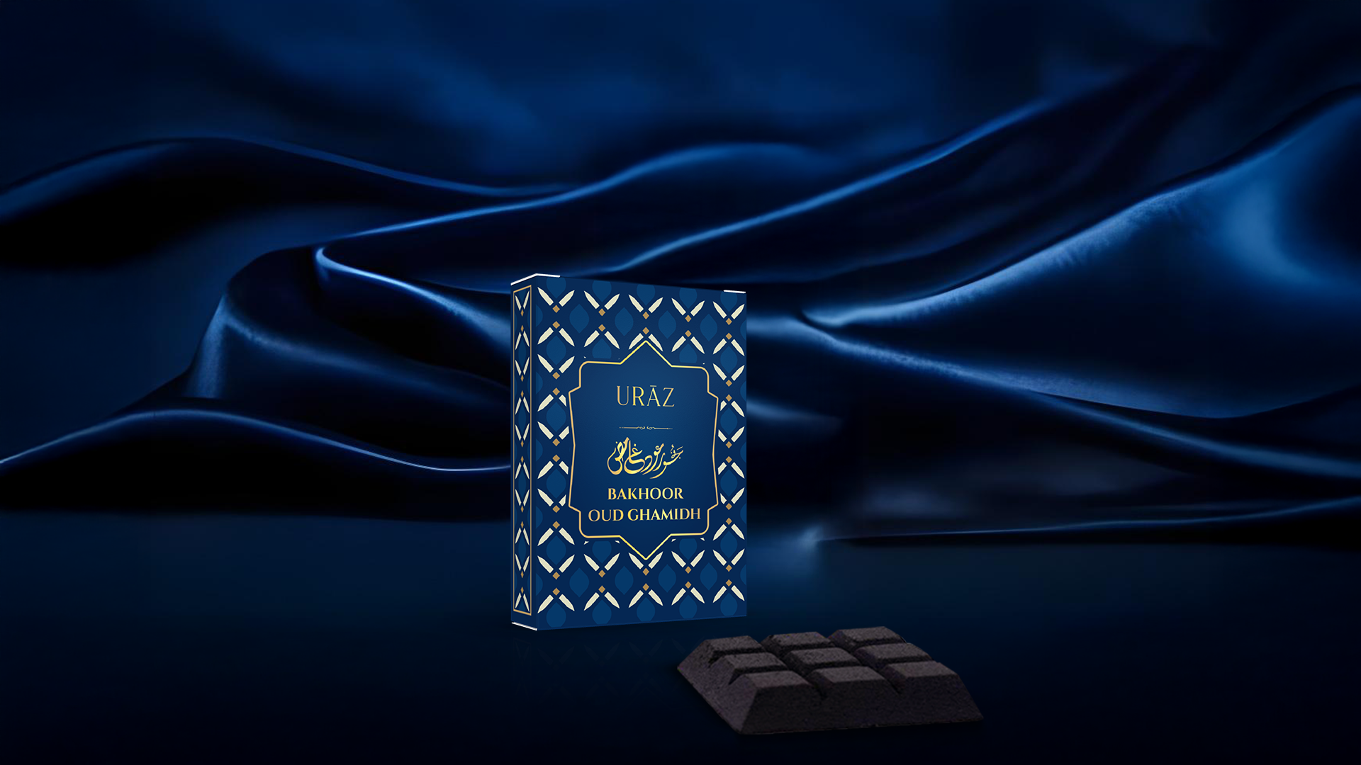 Blue box labelled 'Uraz Bakhoor Oud Ghamidh' on a dark blue fabric background,