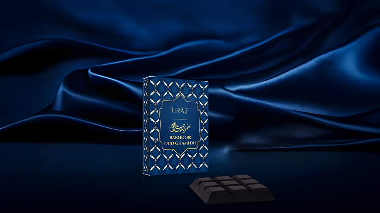 Blue box labelled 'Uraz Bakhoor Oud Ghamidh' on a dark blue fabric background,